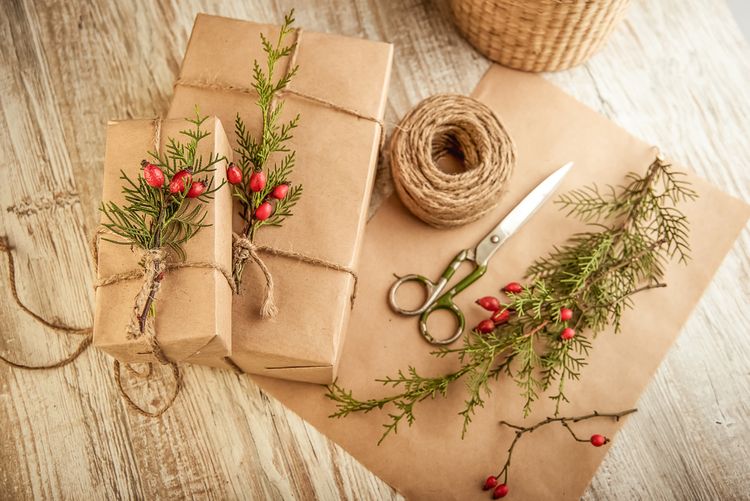 Karácsonyi ajándék egyszerű papírba csomagolva és csipkebogyó gallyakkal díszítve